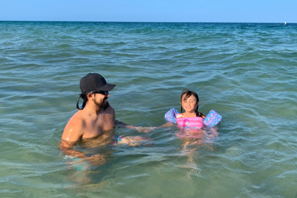 Jessica's daughter playing in the ocean with her dad (Beach More, Stress Less : Beach Day Tips and Hacks Jessica Alvarez-Ducos Contributor Miami Mom Collective)