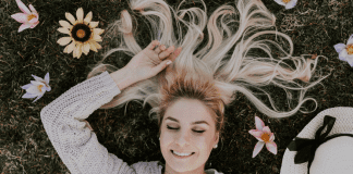 A woman relaxing in field of flowers (National Wellness Month: 6 Easy Ways to Prioritize Your Wellness Today Rachelle Haime Contributor Miami Mom Collective)