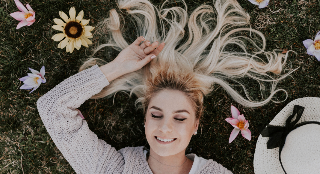 A woman relaxing in field of flowers (National Wellness Month: 6 Easy Ways to Prioritize Your Wellness Today Rachelle Haime Contributor Miami Mom Collective)