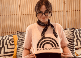 Jacqueline posing with a rainbow t-shirt that reads, "You are enough."