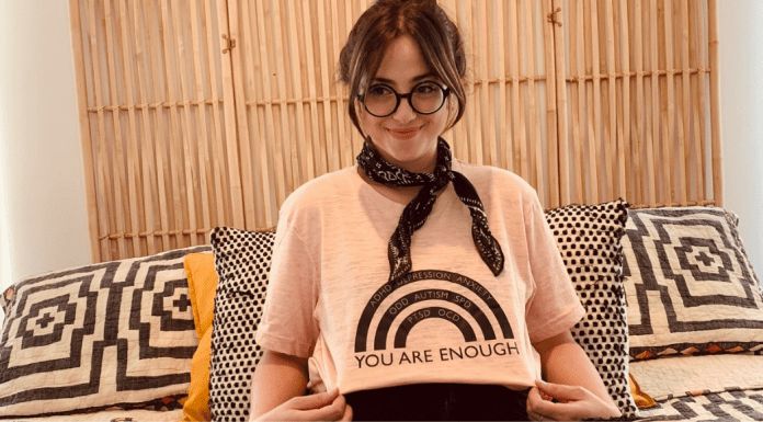 Postpartum Mental Health Disorders: Let’s Break the Stigma Jacqueline posing with a rainbow t-shirt that reads, "You are enough."