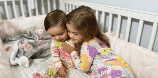 A New Roommate and a New Bed (All at Once!): Our Experience Image: Two sisters snuggling in a crib (A New Roommate and a New Bed (All at Once!): Our Experience Alexa Gonzalez Contributor Miami Mom Collective)