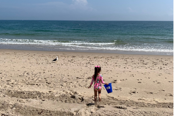 Image: A child carries a bucket on the beach