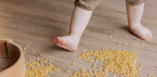 Flat Feet: Does My Child Have Them? Image of a barefoot toddler stepping in dried macaroni that has spilled on the floor.