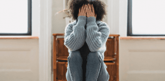 Image: A woman sitting down with her head in her hands (Speak Up: You Matter, Your Opinions Matter Rachelle Haime Contributor Miami Mom Collective)