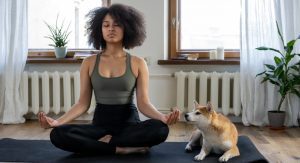 A woman sits cross-legged on a floor mat as she practices meditation