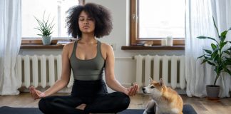 How To Start A Meditation Practice A woman sits cross-legged on a floor mat as she practices meditation