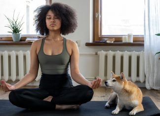 A woman sits cross-legged on a floor mat as she practices meditation