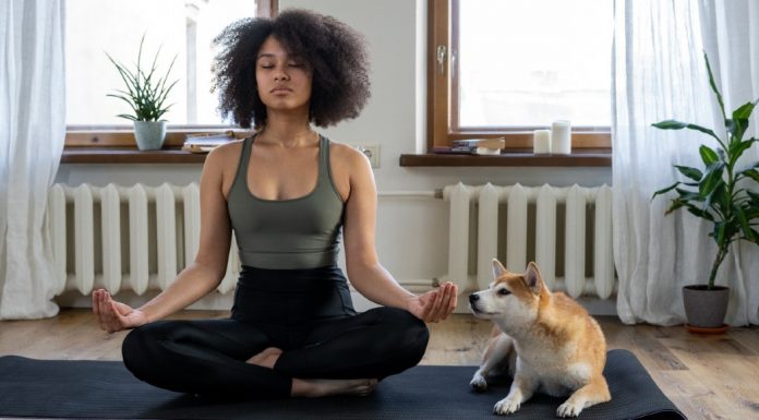 A woman sits cross-legged on a floor mat as she practices meditation
