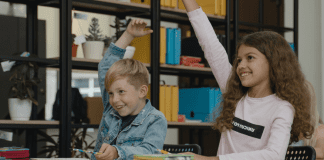 Two students raising their hands (Get Involved: 3 Ways to Help Your Student Succeed Ailyn Quesada Contributor Miami Mom Collective)