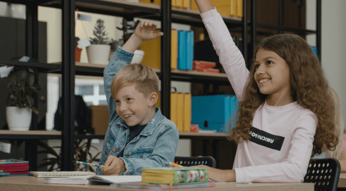 Two students raising their hands (Get Involved: 3 Ways to Help Your Student Succeed Ailyn Quesada Contributor Miami Mom Collective)