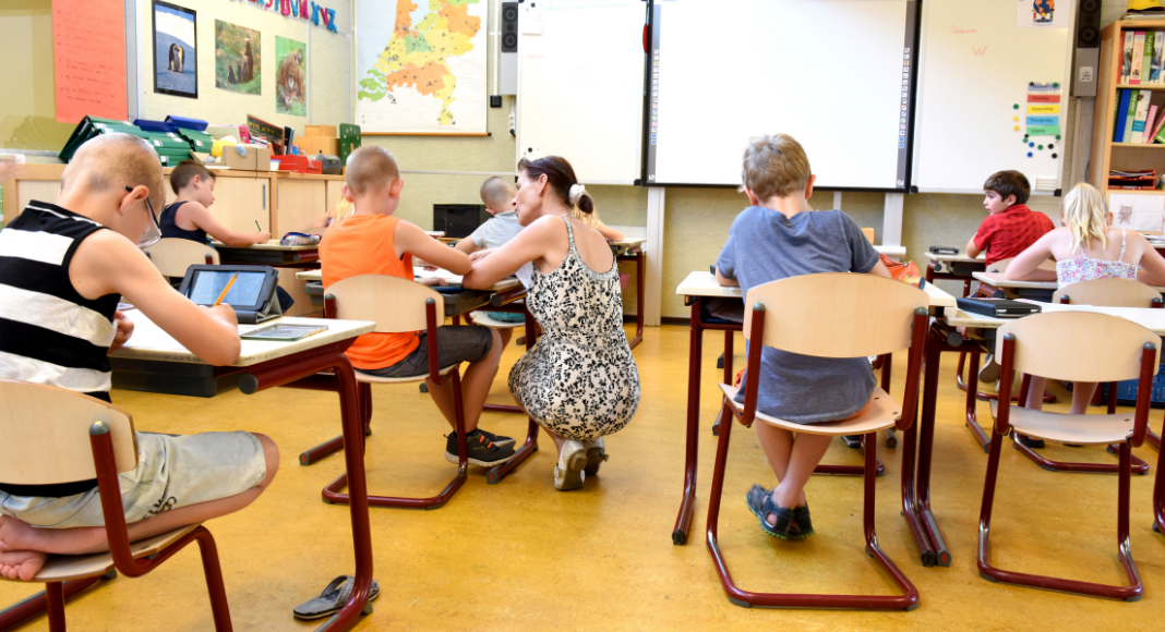 A teacher helping a student in a classroom (Teacher Appreciation Week: Let's Show Appreciation Lorena Lougedo Contributor Miami Mom Collective)