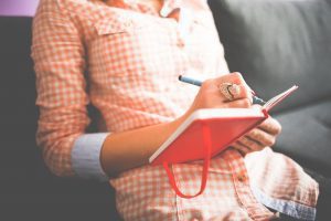 A woman journaling (Stress Awareness Month: The Importance of Checking in With Yourself Rachelle Haime Contributor Miami Mom Collective)