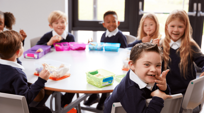 Image Description: several diverse children sit together at a school table for lunch