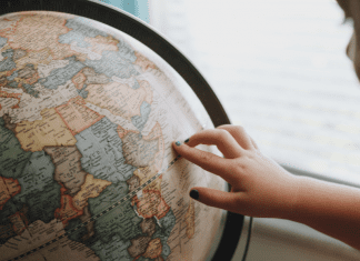 A little girl looking at a globe (Tooth Fairy Traditions From Around The World | Dr. Bob Pediatric Dentist Lynda Lantz Contributor Miami Mom Collective)