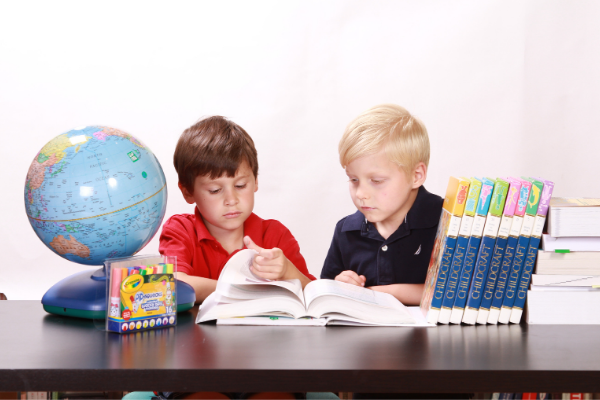 Two classmates looking at an encyclopedia (Let's Celebrate: National Reading Across America Day Lorena Lougedo Contributor Miami Mom Collective)