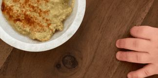 I’m a Dietitian, and I Hated Feeding My Baby Solid Food (At First) | Part 2 A toddler's hand reaching for a bowl of hummus