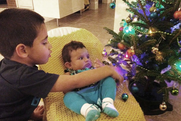 little boy and baby girl next to tiny christmas tree