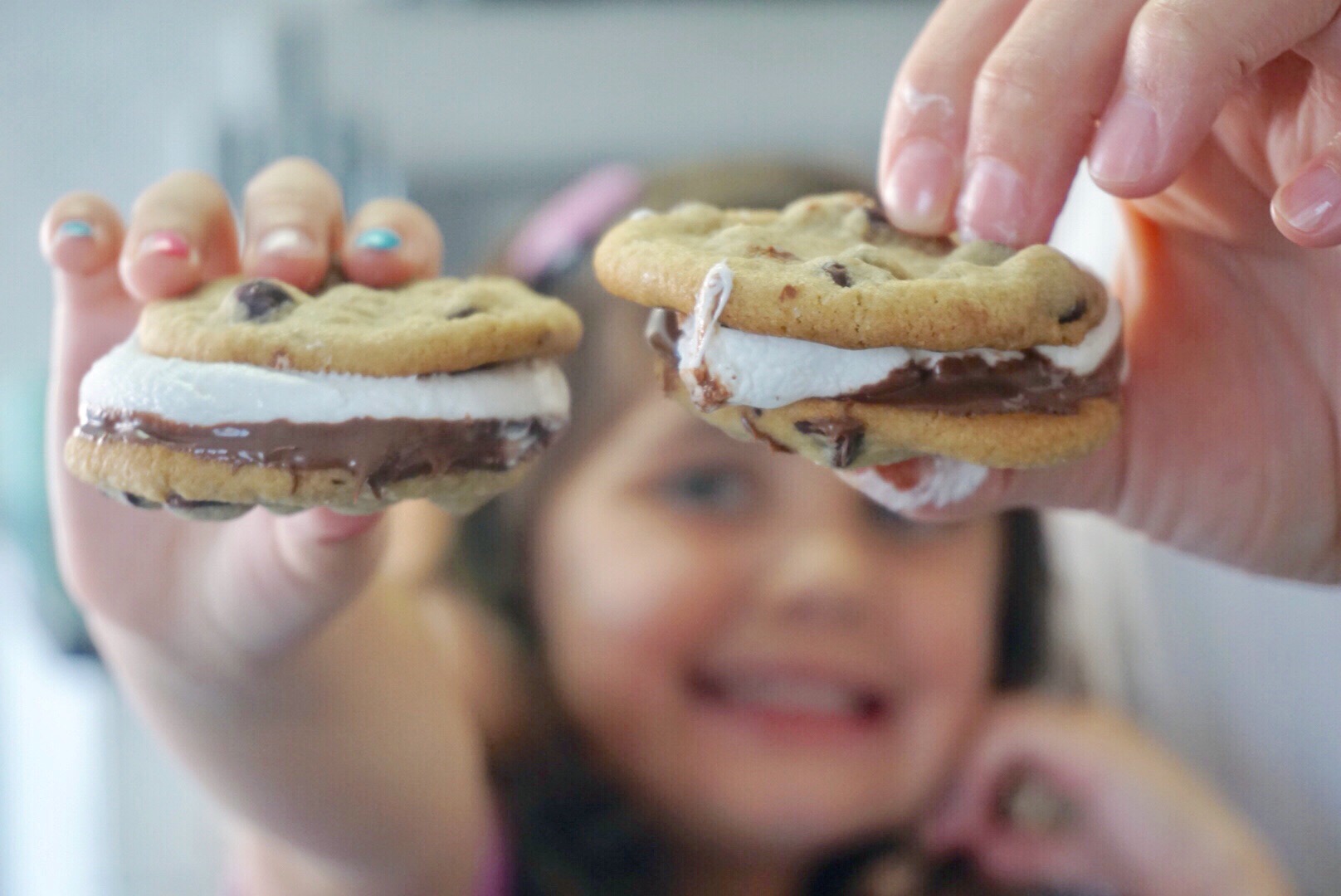 Image: Hands holding chocolate chip cookie s'mores 
