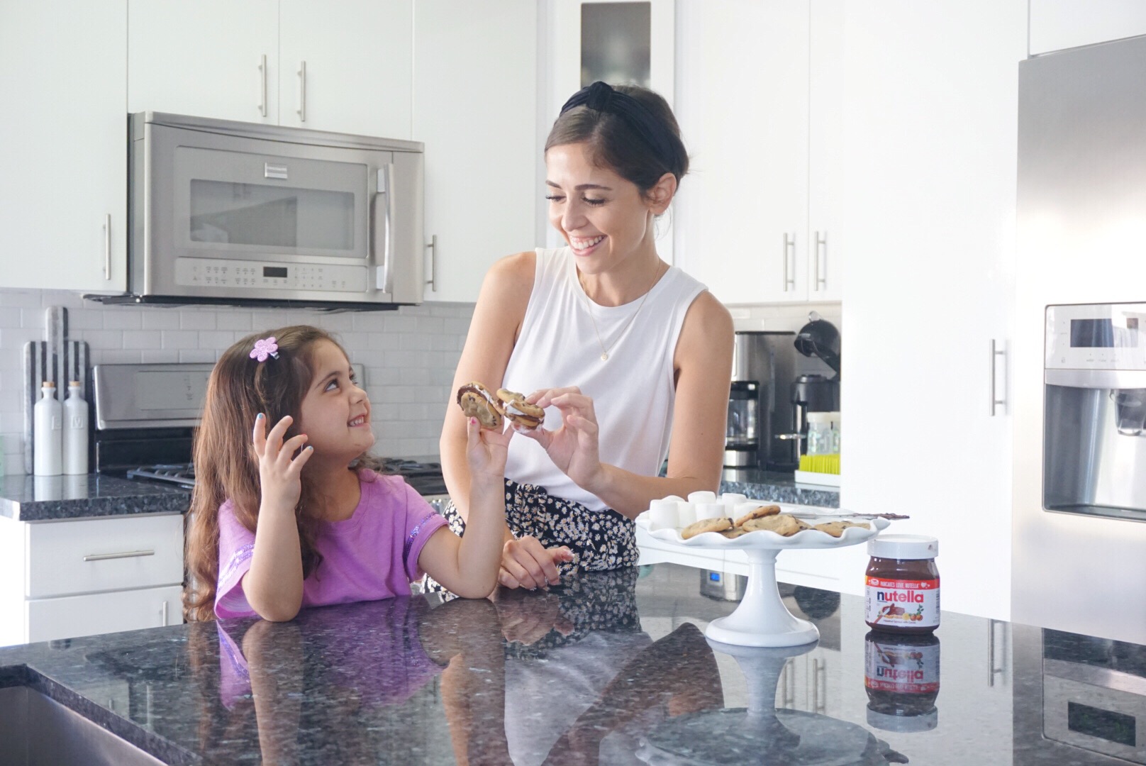 Image: A mother and daughter "cheers" with their chocolate chip cookie s'mores