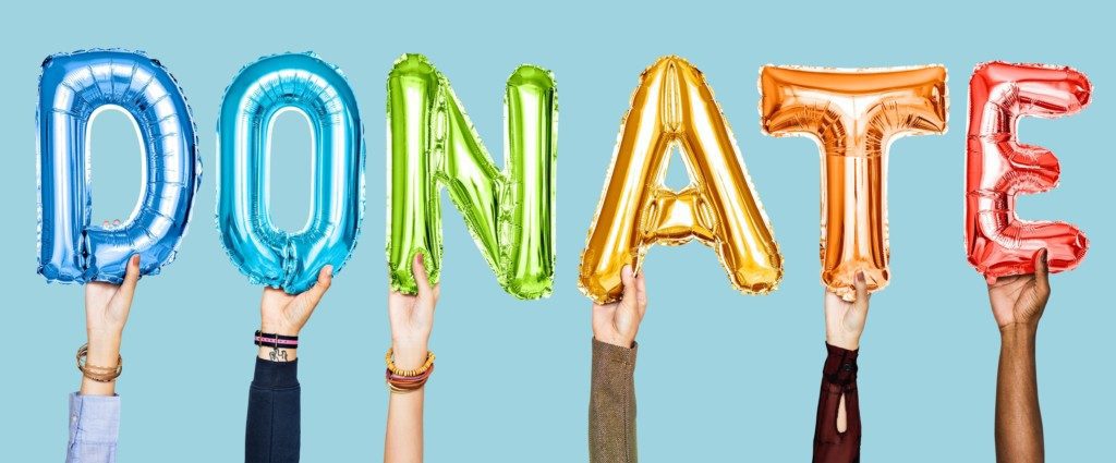 Image: Hands holding up balloons that spell DONATE