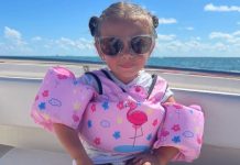 Image: A little girl with a pink swim vest sitting on a boat