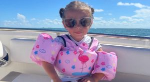 Image: A little girl with a pink swim vest sitting on a boat