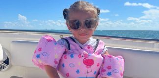 Image: A little girl with a pink swim vest sitting on a boat