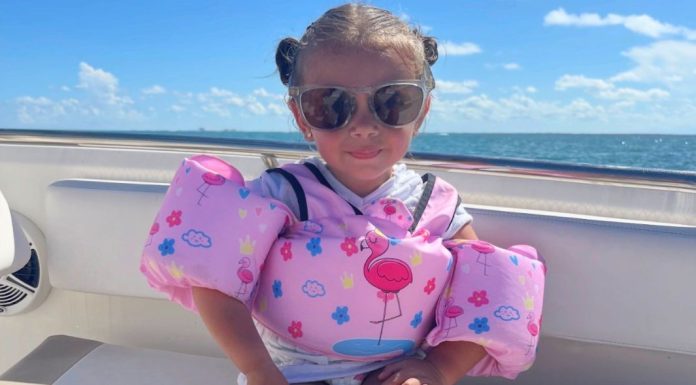Image: A little girl with a pink swim vest sitting on a boat