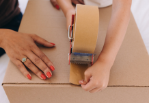 Moving With Kids: What Helped (and What I’d Skip Next Time) Image: A child helps a parent tape a moving box closed
