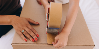 Image: A child helps a parent tape a moving box closed