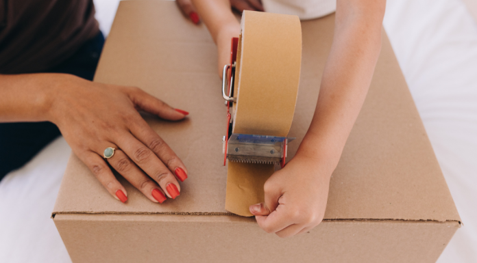 Moving With Kids: What Helped (and What I’d Skip Next Time) Image: A child helps a parent tape a moving box closed