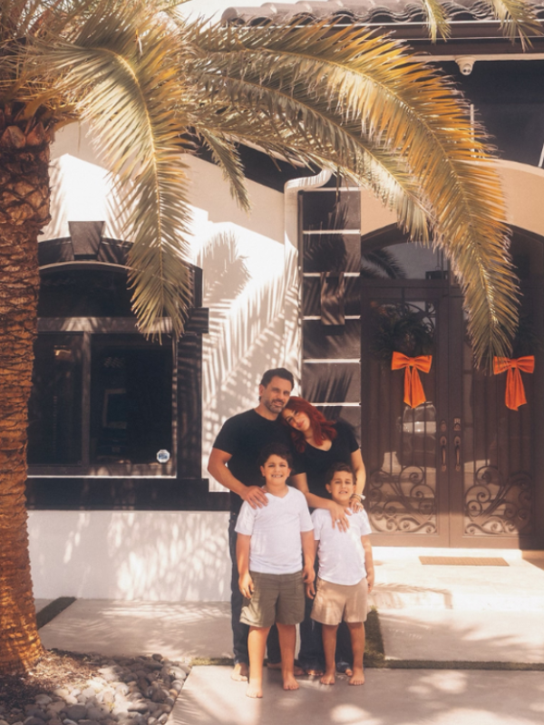 Image: A family poses for a photo in front of their home