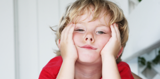 Little boy with hands on his face who appears bored