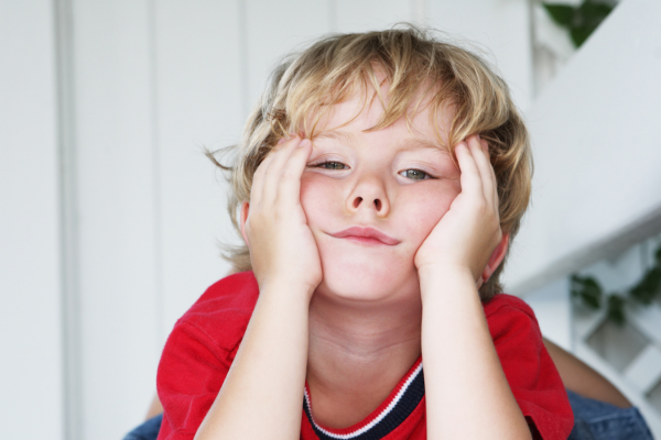 Little boy with hands on his face who appears bored