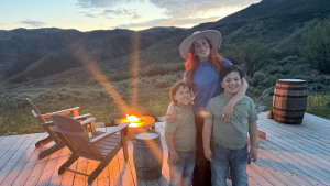 Image: A mother poses for a photo with her children in front of a campfire