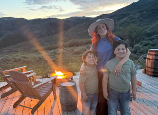 Image: A mom poses for a photo with her kids in front of a campfire