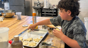 Image: A child places cookies on a baking sheet