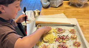 Image: A child decorates cookies on a baking sheet