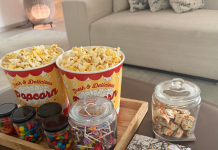 Image: A tray of popcorn and other movie snacks on a living room coffee table