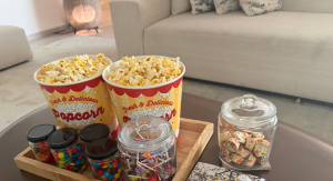 Image: A tray of popcorn and other movie snacks on a living room coffee table