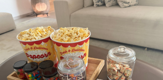 Image: A tray of popcorn and other movie snacks on a living room coffee table