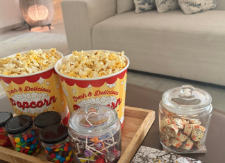 Image: A tray of popcorn and other movie snacks on a living room coffee table