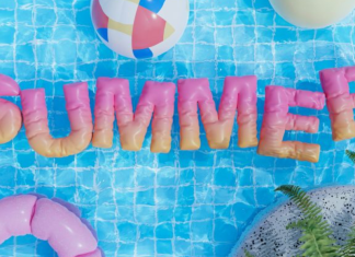 Image: Inflatable letters spelling out SUMMER float on the surface of a pool, framed by beach balls and an inner tube