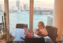 Image: A child sits in front of an open laptop with a view of a skyline behind him