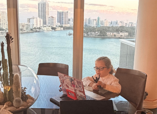 Image: A child sits in front of an open laptop with a view of a skyline behind him