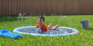 Image: A young child enjoys a splash pad in the backyard