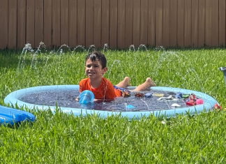 Image: A young child enjoys a splash pad in the backyard