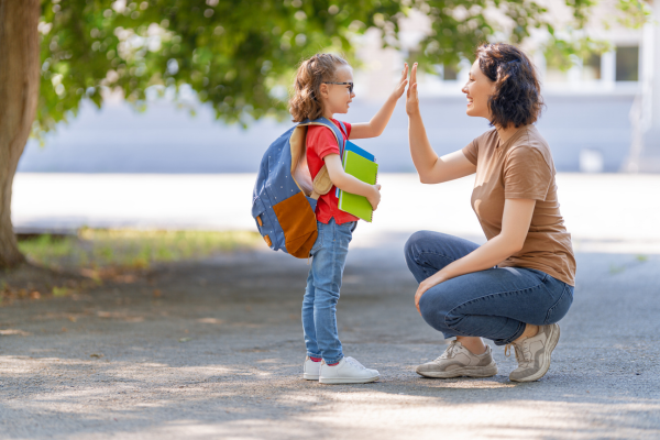 Woman and little girl with a back back high fiving 