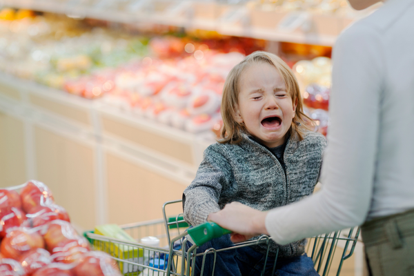 Toddler crying in a shopping cart in the produce section